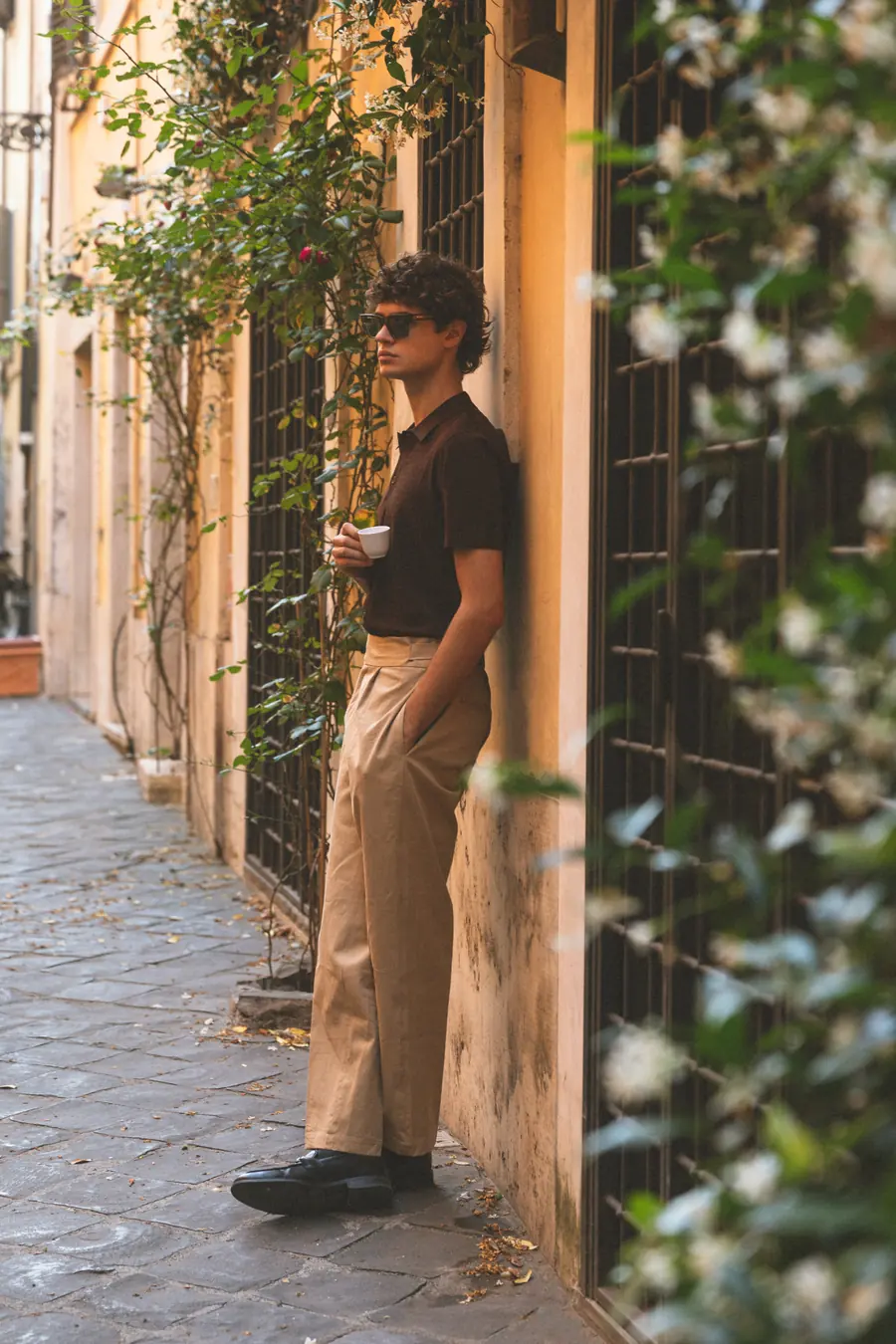 A model leaning on a gate in an alley