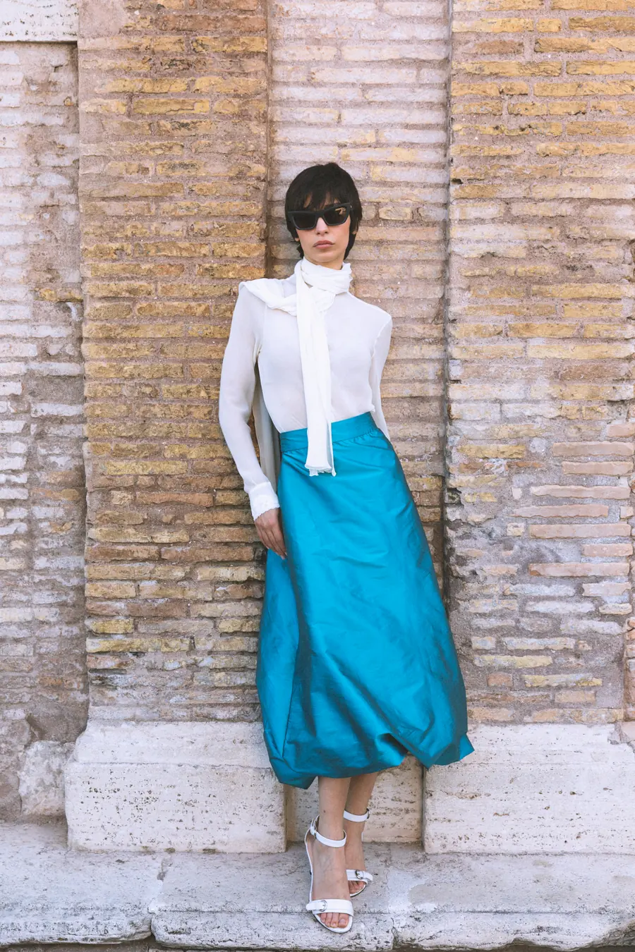 A model standing in front of an ancient brick and travertine wall