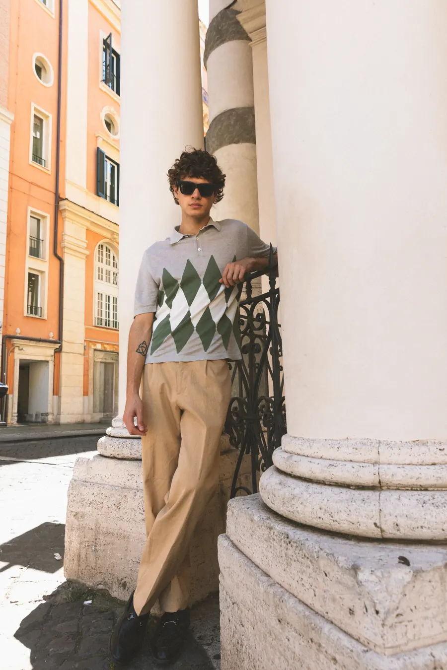 A model leaning on a railing between two columns