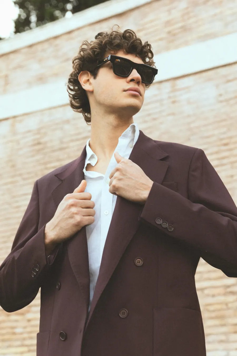 A model looking at the sky in front of a brick wall